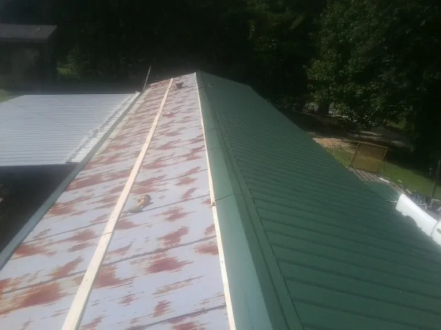 Old rusted panels beside newly installed green metal roofing — Wind Damage Roof Repair by Roofing Brothers in Wharton