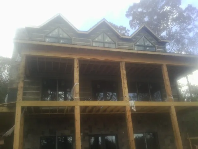 Dormers and porch framing on a large log home under construction — Roof Coating work by our crew in Wharton